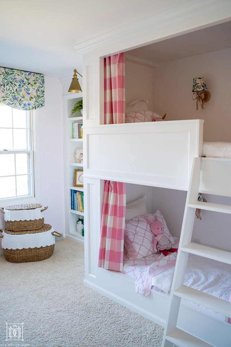 bunk beds with curtains in pink and white buffalo check and a white ladder in girls bunk room shared bedroom