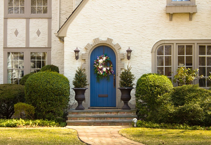 teal arched front door on tan stucco exterior