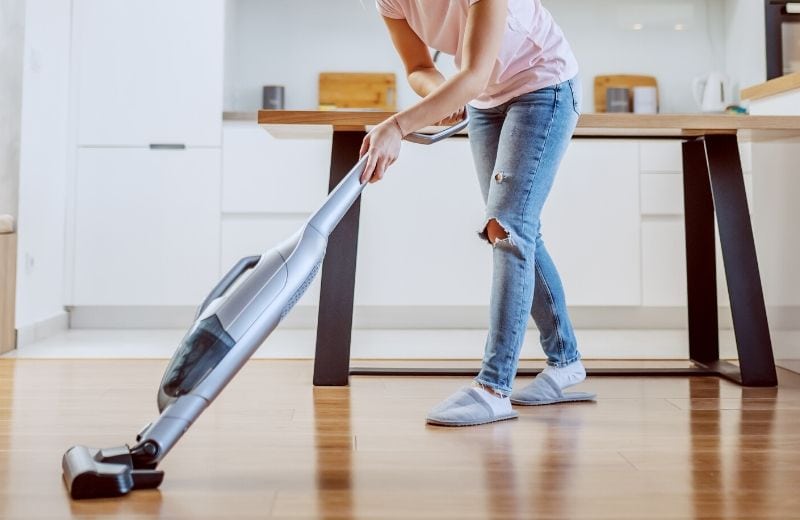 woman using a steam mop on hardwood floors