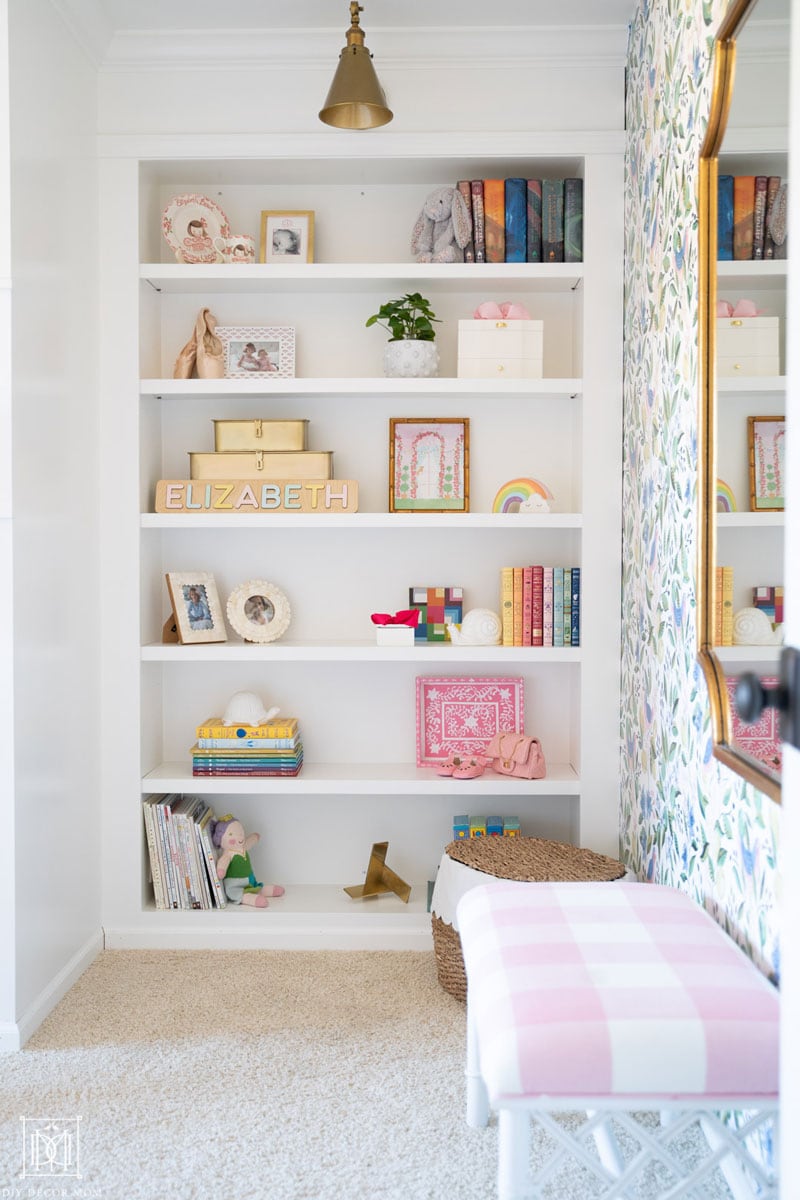 white built-in bookshelves in bedroom with gold sconce