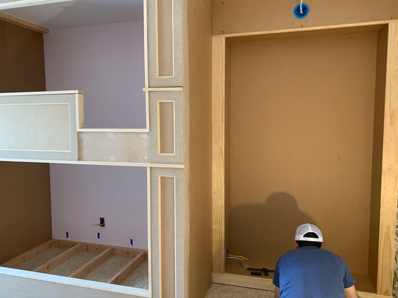 man installing the trim and framing in a built in bookcase