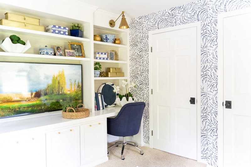 built-in desk with grasscloth bookshelves and blue and white wallpaper on walls