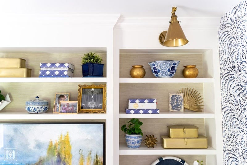 styled built-in bookshelves with faux grasscloth wallpaper backs