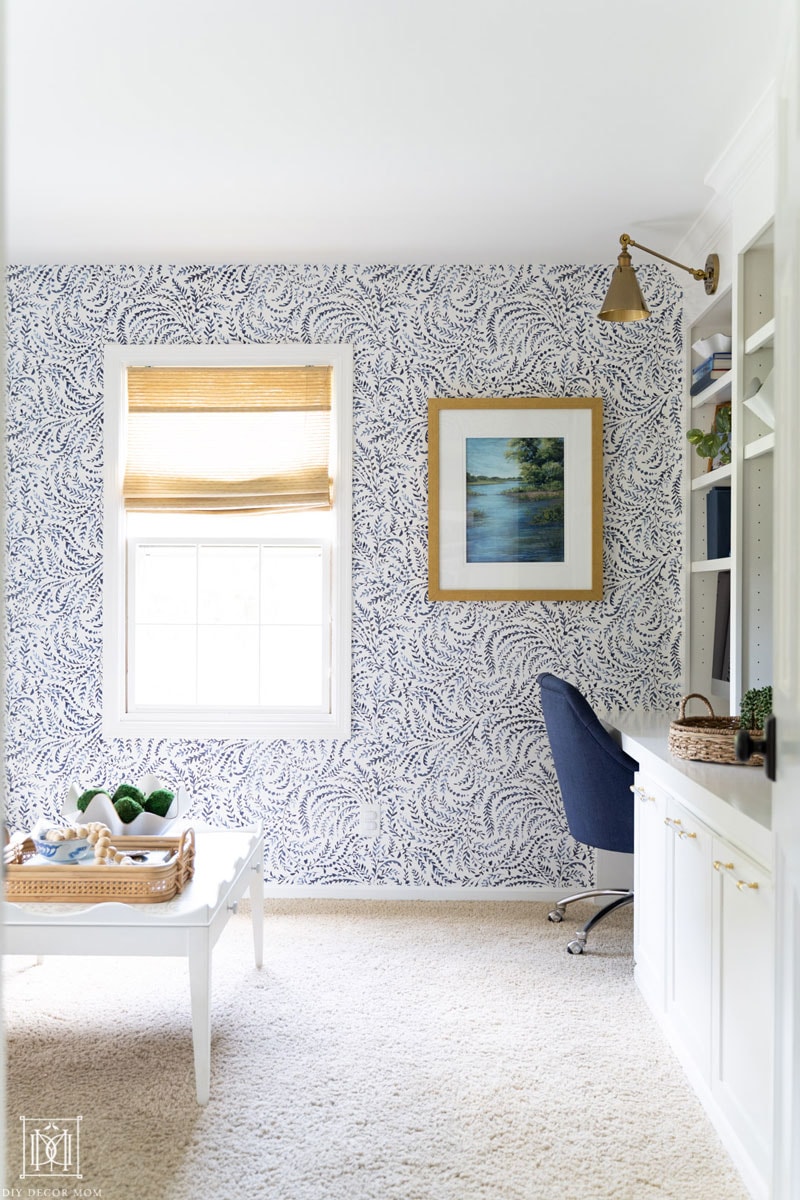 blue and white wallpapered home office with built-in desk and bookshelves